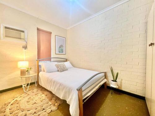 南黑德兰Neat 2 bedroom apartment, with free parking的卧室配有床和白色砖墙