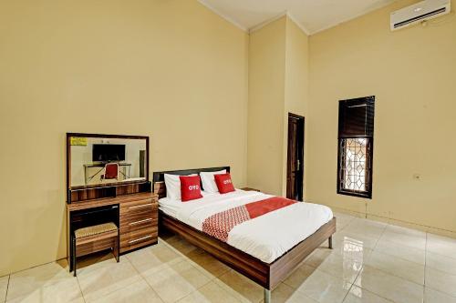SeturanOYO 91522 Candi Gebang Guesthouse的一间卧室配有一张床、梳妆台和镜子