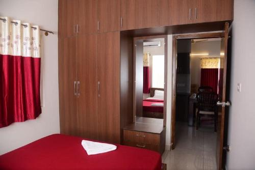 迈索尔The Vihar service Apartment的一间卧室配有红色的床和镜子