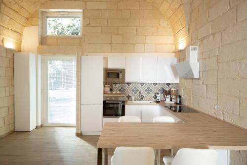 莱切DonCarlo Suite Relais - Free Parking-parcheggio gratuito的厨房配有木桌和白色橱柜。