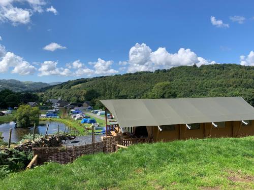 多尔盖罗Quirky Safari Tent with Hot Tub in Heart of Snowdonia的山丘上的帐篷,享有河景