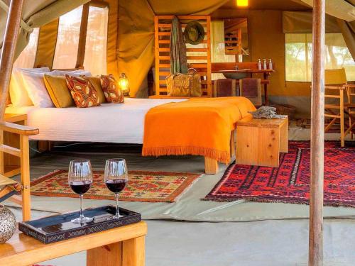 Musiara CampsiteKandili Camp的一间卧室配有一张床和两杯葡萄酒