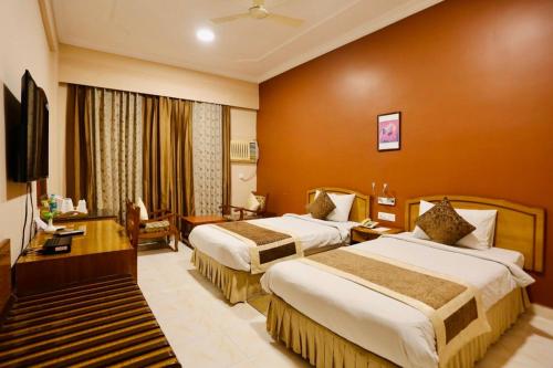 Kushinagar拘尸那迦帝国酒店的酒店客房设有两张床和电视。