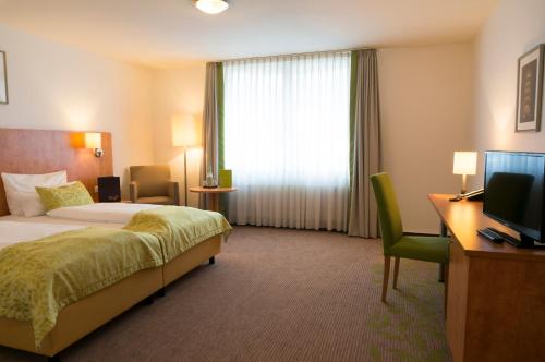 杜塞尔多夫明伽藤酒店的酒店客房配有一张床、一张书桌和一台电视。