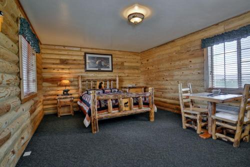 ThayneWolf Den Log Cabin Motel and RV Park的一间卧室设有木墙、一张床和一张书桌