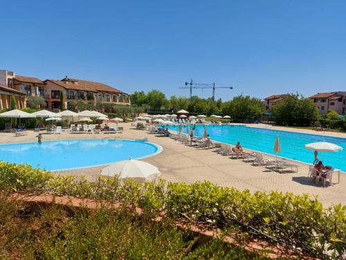 佩斯基耶拉德加达Garda Resort Village I Borghi的一座带遮阳伞的大型游泳池,周围的人可以围着游泳池