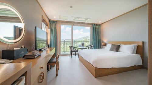 西归浦市J View Hotel的配有一张床、一张书桌和一扇窗户的酒店客房