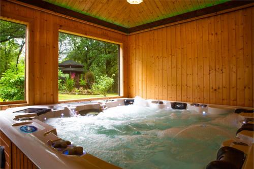 格拉斯哥Stunning 4 bedroom country house - Hot Tub & Sauna的一个带大窗户的客房内的按摩浴缸
