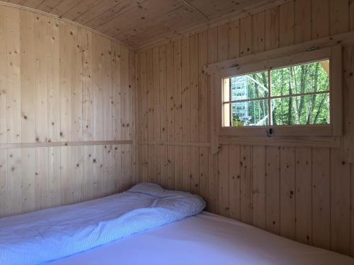 埃尔克海姆Schäferwagen im Herzen vom Unterallgäu的木制客房的一间卧室配有一张床,设有窗户