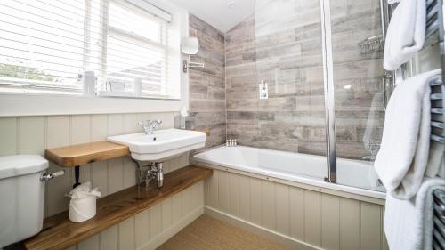 谢伯恩The Sherborne Cottage的浴室配有盥洗盆和浴缸。