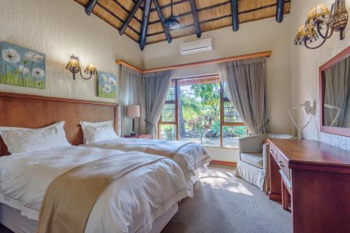 雾观Kruger Park Lodge Unit No. 547的一间卧室设有两张床、一张桌子和一个窗口。