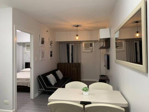 马尼拉Cozy 1 Bedroom near Alabang Town Center and Molito with Wifi and Netflix的客厅配有桌椅和1张床