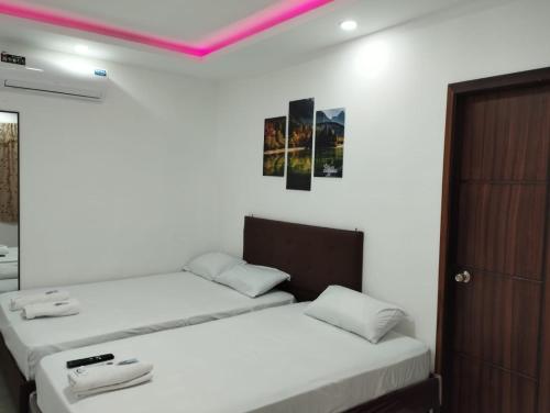 曼塔Hostal Las Orquideas的一间卧室设有两张床和粉红色的天花板