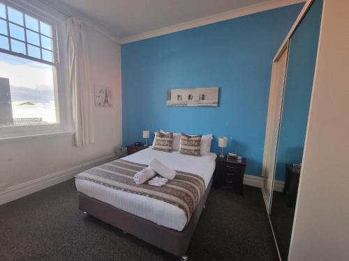 墨累桥第六小屋旅舍的一间卧室配有一张蓝色墙壁的床和一扇窗户