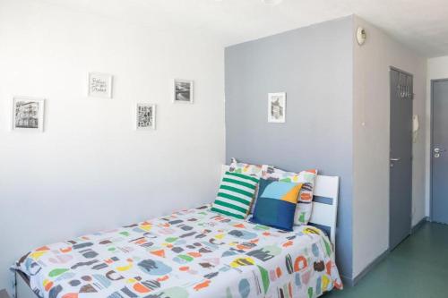 里昂帕特迪尤一室公寓的一间卧室配有一张带五颜六色棉被的床