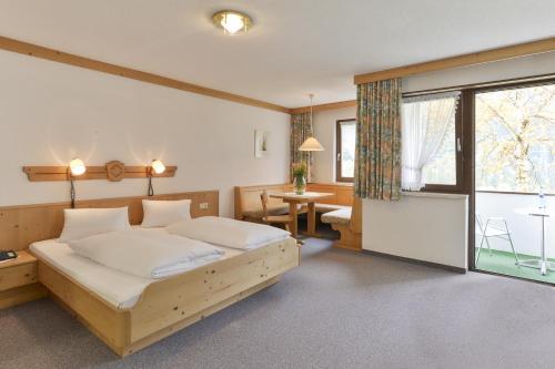 瓦尔德阿尔贝格Hotel Sonnblick的一间卧室配有一张床、一张桌子和一个窗户。