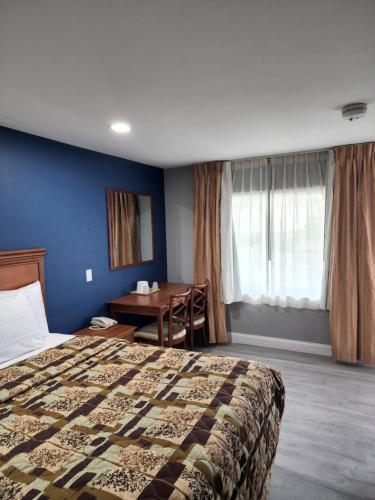 霍斯黑兹Budget Inn Horseheads的酒店客房配有一张床铺和一张桌子。