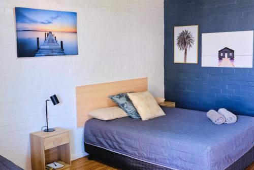 马拉库塔Mallacoota Hotel Motel的一间卧室设有一张床和蓝色的墙壁