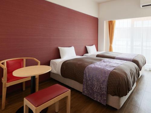 读谷村ミチ旅ホテル 読谷的酒店客房,设有两张床和一张桌子及椅子