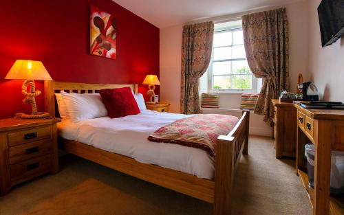 达特茅斯The Ship in Dock Inn的一间卧室设有一张红色墙壁和窗户的床