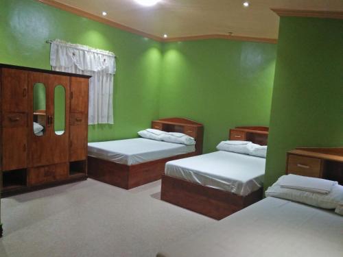 曼巴豪Villa Corrales Homestay的带三张床和绿色墙壁的客房