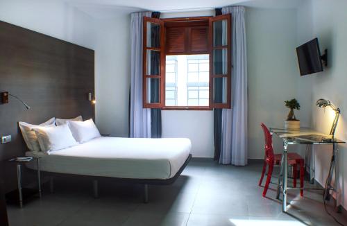 瓦伦西亚Quart Youth Hostel & Apartments的一间卧室设有一张床、一个窗口和一张桌子