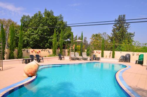 Arbel阿贝尔沙维特家庭宾馆的庭院内的游泳池,配有桌椅