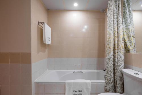 迪拜Easy Click - Superior Quality 1 Bed in Greens的带浴缸和淋浴帘的浴室
