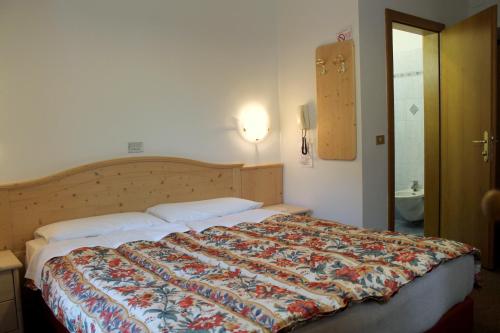 莫埃纳特伦蒂诺酒店的一间卧室配有一张大床和五颜六色的被子