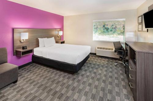 休斯顿休斯顿西南拉库恩塔酒店及套房的酒店客房带一张床和紫色的墙壁