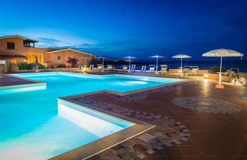 阿兰奇湾城Appartamenti Marineledda Golfo di Marinella的夜间带遮阳伞的游泳池