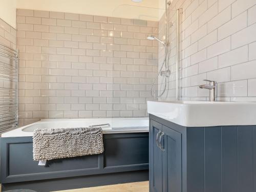 斯托尔河畔希普斯顿The Paddock的浴室配有蓝色水槽和浴缸。