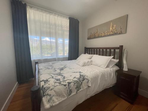 Okanagan FallsKaleden Guest Suite的一间卧室配有一张带白色床单的床和一扇窗户。