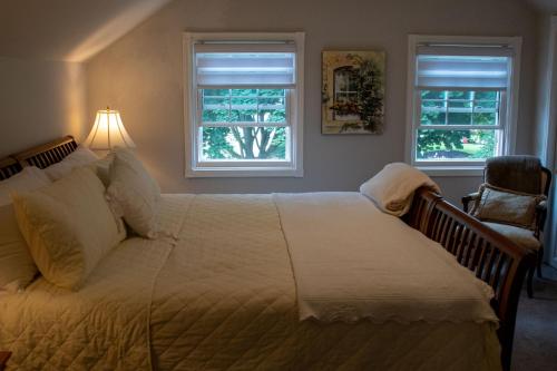 滨湖尼亚加拉Upper Canada Coach House的一间卧室设有一张大床和两个窗户。