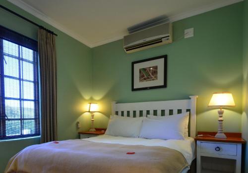 德班维尔D'Aria Guest Cottages的一间卧室设有绿色的墙壁和一张带两盏灯的床。