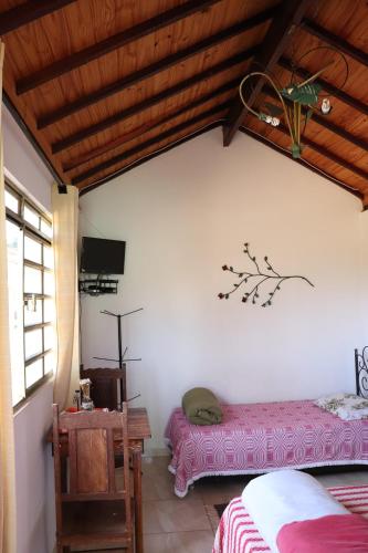 圣托梅-达斯莱特拉斯Chalés Excalibur的一间卧室配有一张床、一张桌子和一台电视。