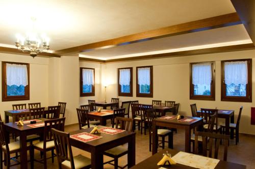 波尔塔里亚贝利娜酒店的餐厅设有木桌、椅子和窗户。