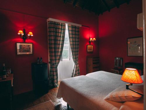 洛西洛斯卡萨阿马里利亚田园酒店的卧室设有红色的墙壁、一张床和窗户
