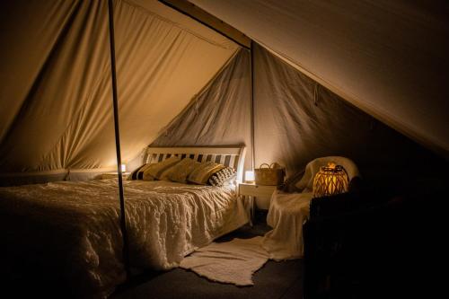 MuurameHideaway Glamping的一间卧室配有一张床铺,帐篷内提供一把椅子