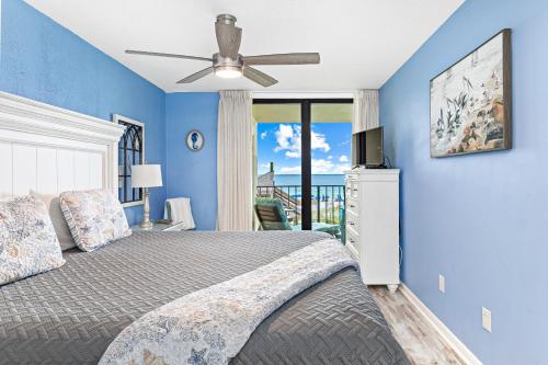 奥兰治比奇Updated Beachfront 2 BR 2 Bath Condo with direct views of the beach的一间卧室设有蓝色的墙壁和一张带吊扇的床。