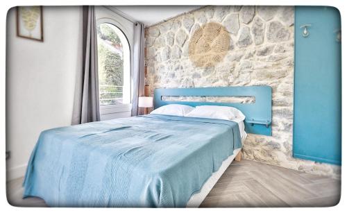 芒通Le Vallaya Suites & Spa的一张蓝色的床,位于一个石墙房间内