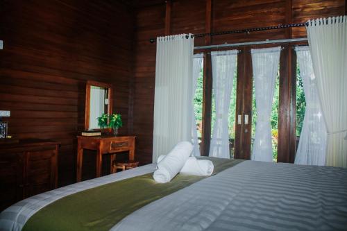 珀尼达岛Kurnia Guest House & Spa的一间卧室配有床和白色窗帘的窗户