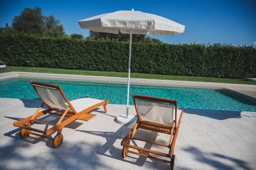 奇斯泰尼诺Dimorae Camà的游泳池旁的两把椅子和一把遮阳伞