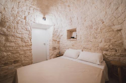 奇斯泰尼诺Dimorae Camà的卧室配有石墙内的白色床