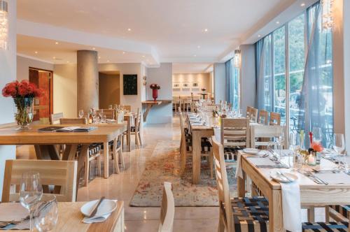 开普敦开普敦豪鲁精品酒店的餐厅设有木桌和椅子以及大窗户。