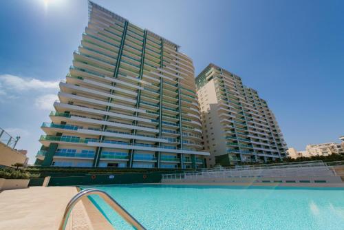 斯利马斯利马海滨公寓的一座大型建筑,前面设有一个游泳池