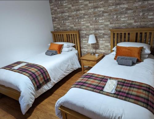 库申多尔Antrim Coast Apartments的一间卧室设有两张床和砖墙