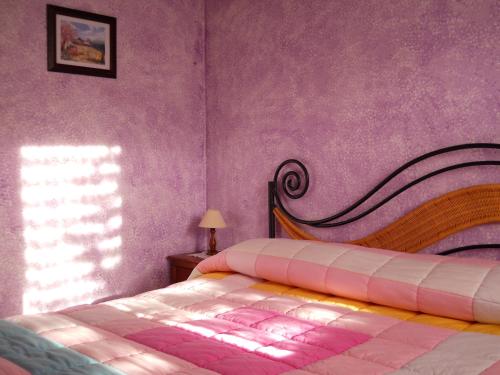 文蒂米利亚松鼠农家乐的一间卧室配有一张床和紫色的墙壁