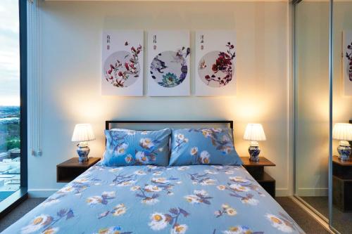 阿德莱德Luxury City Zen Apartment Rundle Mall with Rooftop Spa, Gym, BBQ的一间卧室配有一张蓝色的床,墙上有三幅画作