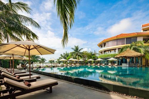 会安Bel Marina Hoi An Resort的度假酒店的游泳池配有躺椅和遮阳伞